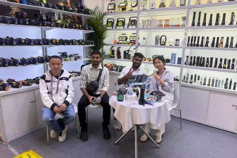 PLD team seated with buyers at the booth table, work lights and flashlights on the shelves behind